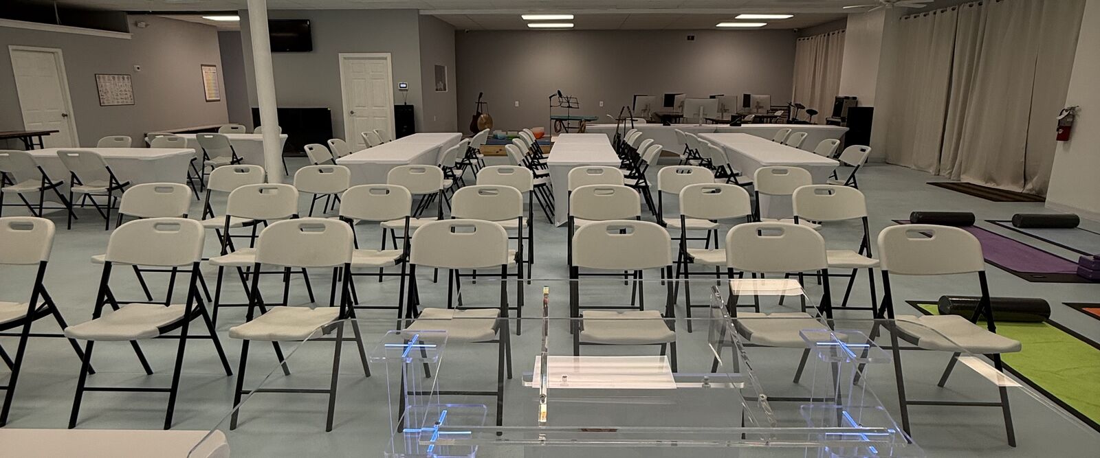 A spacious room with white walls, equipped with rows of chairs